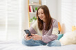© New Africa - Teenage girl using smartphone on bed at home