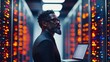 © Chanwit - Thoughtful black man with laptop stands in a server room managing data and cloud computing infrastructure.