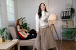 © Parichat - Asian women are enjoying their free time playing the guitar and singing in the living room