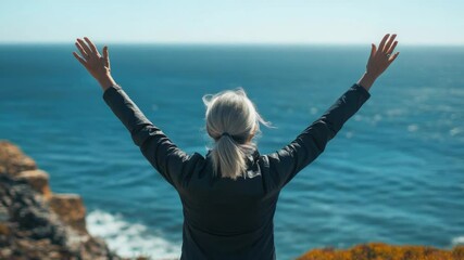 Poster - A person standing at the edge of a cliff looking out at the vast ocean