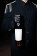 © Mykhailo Feriukov - Premium Bottle Presentation.Close-up of a hand in black gloves holding a luxurious liquor bottle against a dark formal uniform, conveying elegance, exclusivity, and sophistication.