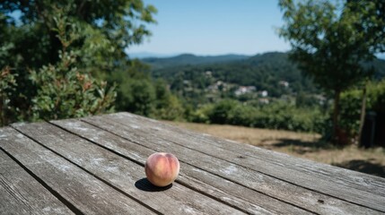 Aufkleber - A ripe peach rests on a weathered wooden table, illuminated by warm afternoon light with a scenic hillside view in the background, creating a tranquil atmosphere