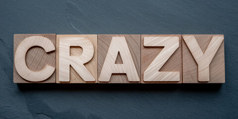 Poster - Wooden blocks spelling CRAZY on dark gray background, showcasing a bold and energetic concept