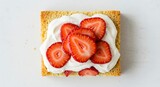 Overhead View Of Square Cake With Whipped Cream and Sliced Strawberries on White Surface