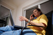 © Taras Grebinets - Woman in a Yellow Shirt Using a Laptop and Phone Outdoors