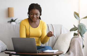 Aufkleber - Millennial African Lady In Headset Watching Webinar On Laptop At Home, Having Online Training, Studying With Computer And Taking Notes To Notepad, Enjoying Distance Learning, Copy Space