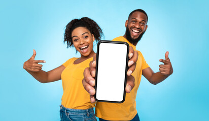 Poster - Use this new mobile app. Joyful African American couple pointing at smartphone with empty white screen, advertising your website, mockup. Selective focus. Banner design