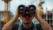 © dlu - Man Using Binoculars at Construction Site