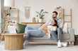 © Pixel-Shot - Happy pregnant couple resting on sofa at home