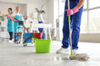 © Pixel-Shot - Male janitor mopping floor and his team cleaning in office