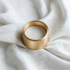 Poster - Minimalist composition of golden cylinder on soft white fabric surface, top view