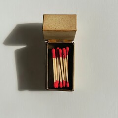 Poster - Open matchbox with red tipped matches casting shadow on white background overhead minimalist studio shot