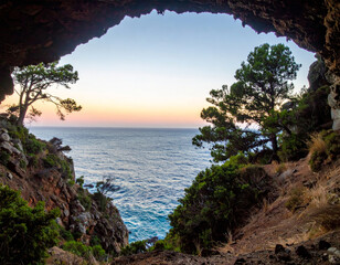Wall Mural - stunning coastal view framed by rocky cave, showcasing serene ocean and vibrant sunset colors. scene evokes sense of tranquility and natural beauty