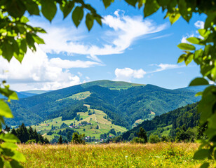 Wall Mural - stunning mountain landscape framed by lush green leaves, showcasing rolling hills, vibrant greenery, and clear blue sky with fluffy clouds. serene view evokes sense of peace and tranquility