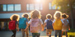 © guguart - Educational background. Back to school concept with a group of children walking happily on a backpack walking to the school building in the sun