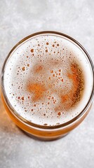 Poster - Refreshing beer in glass overhead shot with foamy head and bubbles on gray surface perfect for summer or celebration