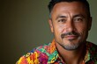 © Vibu design  gallery - Close-up portrait of a smiling man with short graying hair wearing a vibrant floral shirt.