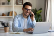 © Nishat Begum - Smiling Caucasian Man with Glasses Talking on Phone and Using Laptop at Desk