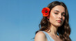 © Vasiliy - Woman with wavy brown hair and red poppy flower behind ear against blue background. Natural floral beauty concept for summer fashion, cosmetic advertising and seasonal accessories marketing