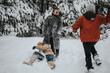 © qunica.com - Three friends having fun in a snowy forest, engaging in cheerful snow activities. The winter setting emphasizes the joyful bond between friends enjoying outdoor adventures among beautiful snow-covered