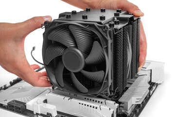 Poster - A person is installing a large black tower-style CPU cooler with a fan onto a motherboard during PC assembly.