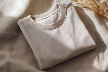 Poster - A Folded T Shirt Flat Lay on Neutral Textured Fabric with Decorative Collar Providing Apparel Mock Up Inspiration and a Focus on Clothing