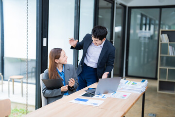 Poster - Two asian businesspeople discussing and working together with happy emotion and using laptop computer, tablet and paperworks in modern office workplace