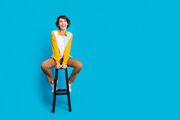 Poster - Photo of positive girl feel carefree excited sit chair look empty space isolated blue color background