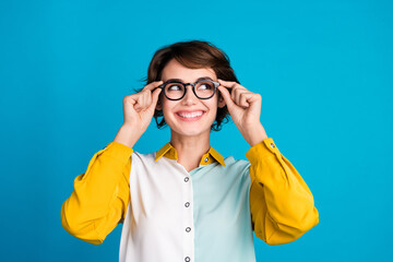Poster - Portrait of bob hair lady in formal shirt with yellow sleeves touch glasses look empty space vision fixed isolated on blue color background