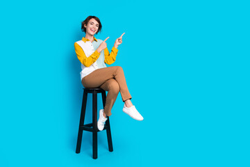 Poster - Photo of positive girl trader sitting stool demonstrate sale discount isolated blue color background