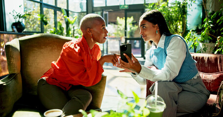 Fototapete - Phone, business women and discussion in cafe for idea, brainstorming or show eco friendly project online. Mobile, team meeting and planning in coffee shop for proposal with sustainability consultant