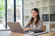 © wattana - Professional woman working on important project remotely from stylish office desk.