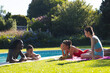 © Wavebreak Media - Smiling Diverse friends in swimwear chatting poolside on lawn, with fruit platter on pink towel