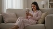 © AlfaSmart - Woman relaxing at home in cozy pajamas using smartphone