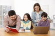 © New Africa - Parents helping their kids with homework at wooden table indoors