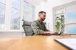 © New Africa - Man working on laptop at desk in office, low angle view