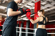 © New Africa - Woman in protective gloves having boxing practice with her coach at training center