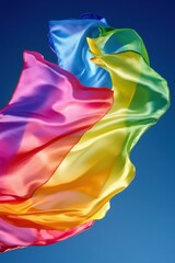 Poster - Rainbow silk scarves flowing against a clear blue sky, vibrant colors in motion, low angle shot, bright and airy, studio