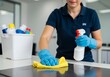 © Muaz - Woman cleaning surface with rag and spray bottle in office setting