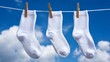 © Tida - Three White Socks Drying in the Sun - Three clean white socks hang on a clothesline, drying in the sun. Symbols of freshness, cleanliness, simplicity, laundry day, and sunshine