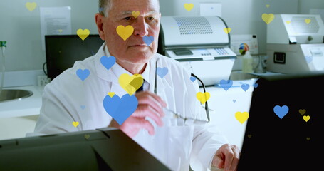 Poster - Image of yellow and blue hearts falling over senior caucasian male lab worker with computer