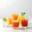 © Hamza - A variety of colorful beverages in clear glasses arranged on a white surface in a studio setting