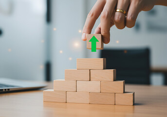Poster - Hand placing wooden block with upward arrow on growing pyramid structure symbolizing business growth success strategy planning achievement