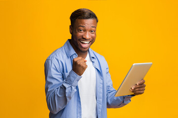 Aufkleber - Cheerful African American Guy Holding Digital Tablet Gesturing Yes Standing On Yellow Background. Studio Shot