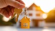 © upnowgraphics - Hand holding keys with a house keychain and background house