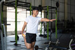 © Natee Meepian - Wellness through Stretching. Young man performing leg stretch at gym.