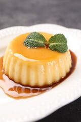 Wall Mural - delicious pudding with caramel sauce and mint on gray table, closeup