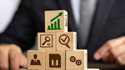 Poster - Man stacking wooden blocks with business icons on table in suit jacket for strategy planning concept