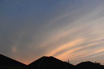 Wall Mural - roof of house on beautiful golden sky and white cloud background in springtime