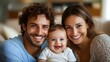 © CHAIYAPHON - A happy young family portrait shows a smiling mother father and their adorable baby at home.